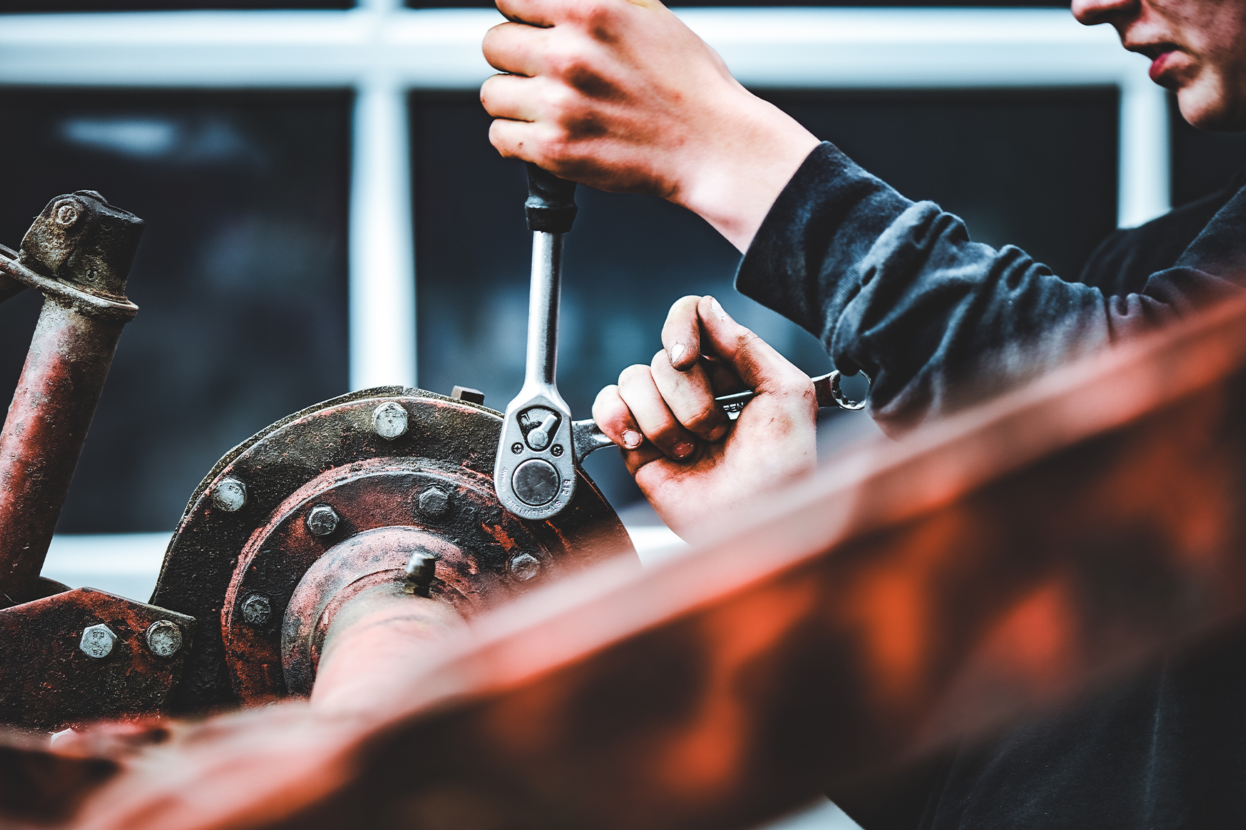 a man using a wrench tool to work on farm equipment