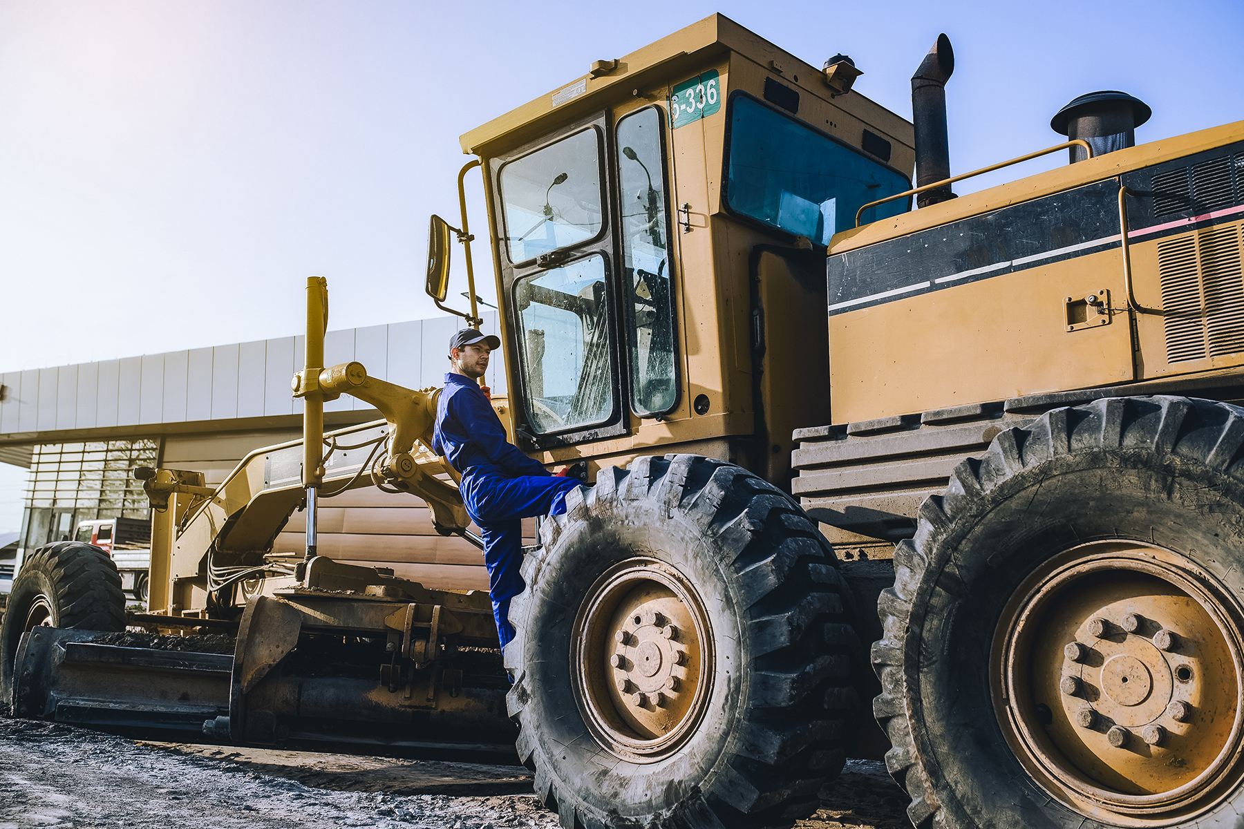 a young man climbing up into a piece of heavy machinery